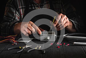 Installation of an electrical cable or wire in a gray junction box by the hands of a master electrician