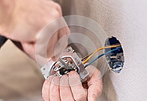 Installation of electrical sockets. Hands an electrician installing an electrical network in a new house. Selective focus on the