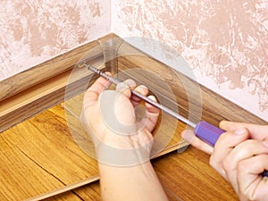 Installation and fixing of the baseboard,mounting and assembly plinth,the master screws the skirting board closeup