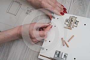 A woman inserts wooden pins into the sidewall of the furniture w