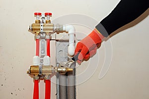 Installation individual of home heating. A plumber attaches the tube to the collector heating. Underfloor heating installation.