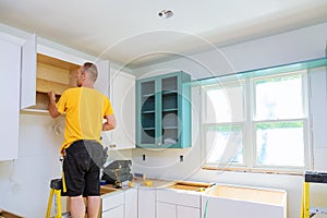 Installation of kitchen. Worker installs doors to kitchen cabinet.