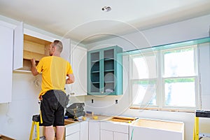 Installation of kitchen. Worker installs doors to kitchen cabinet. photo