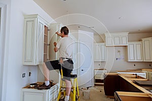 Installation of kitchen. Worker installs doors to kitchen cabinet.