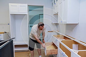 Installation kitchen. Worker installs doors to kitchen cabinet.