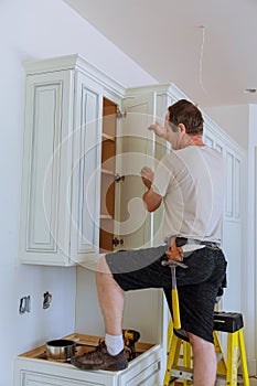 Installation of kitchen. Worker installs doors to kitchen cabinet.