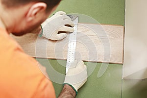 Installation laminate or parquet in the room, worker installing wooden laminate flooring, marking the length of the