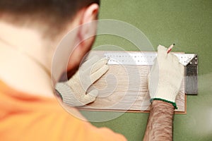 Installation laminate or parquet in the room, worker installing wooden laminate flooring, marking the length of the