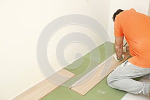 Installation laminate or parquet in the room, worker installing wooden laminate flooring, marking the length of the