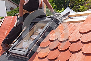 Installation of mansard windows on a new roof of red tiles.