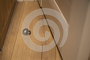 Installation metal door stopper on wooden floor with screwdriver