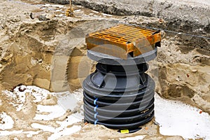 Installation of a new modern plastic rainwater drainage well with cast iron grate in the city street