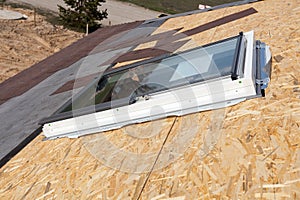 Installation of new plastic mansard or skylight window on a asphalt shingle roof.