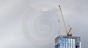 Installation of panoramic windows on a skyscraper with a crane. High-rise construction. Glass facade of a high-rise