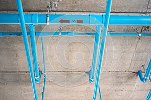 Installation of pipes of water supply systems in buildings. Blue PVC pipe under cement ceiling. Construction of a house.