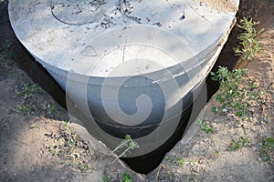 Installation of a septic tank made of concrete rings. Concrete sewer well, manhole rings installation into a square hole