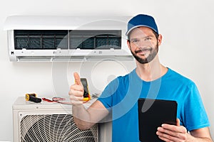 Installation service fix  repair maintenance of an air conditioner indoor unit, by cryogenist technican worker giving thumbs up