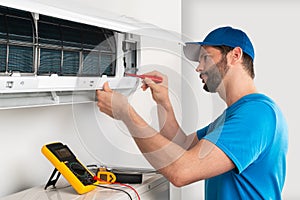 Installation service fix  repair maintenance of an air conditioner indoor unit by cryogenist technican worker with screwdriver photo