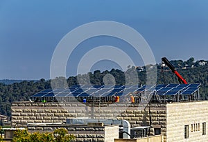 Installation of solar cell electric panels on a roof of multi-storey building in Israel. Solar panels on the house roof. Workers