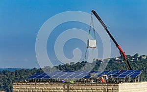 Installation of solar cell electric panels on a roof of multi-storey building in Israel. Solar panels on the house roof. Workers