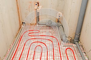 Installation water underfloor heating pipes on the silver reflective material in house construction.