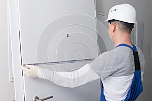 Installation wizard, measures the door with a tape measure, before replacing it