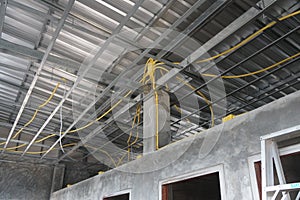 Installation of yellow PVC conduit pipes under metal sheet roof trusses. Galvanized steel, C-Line Galvanized.