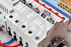 Installed automatic circuit breakers on DIN rail in white plastic mounting box closeup