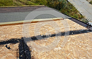 Installing asphalt shingles on the roof. A  close-up of asphalt shingles installation layers: waterproofing OSB sheathing with tar