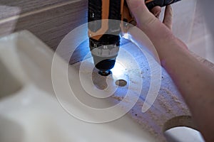 Installing a bathroom sink on a wooden countertop. Drilling a hole with a drill