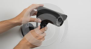 installing a black security camera on a white wall