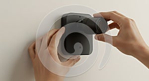 installing a black security camera on a white wall