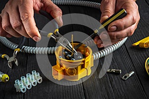 Installing a cable or wire to a junction box. Electrical connection in the workshop of professional master electrician. Close-up