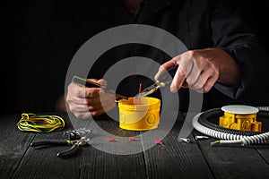 Installing a cable or wire to a junction box. Electrical connection in the workshop of professional master electrician. Close-up