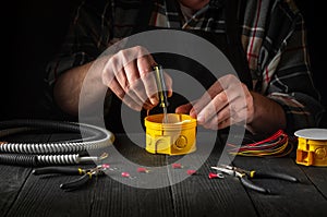 Installing a cable or wire to a junction box. Electrical connection in the workshop of professional master electrician. Close-up