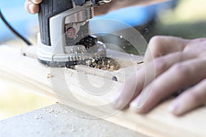 Installing a door, Install a door lock, use a milling saw, a carpenter close-up holds a green electric drill