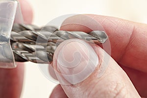 Installing a drill bit in a drill, hands take a drill and install it in a cordless drill chuck