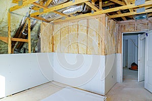 Installing plasterboard sheet to wall for attic room construction at the attic termal insulation photo