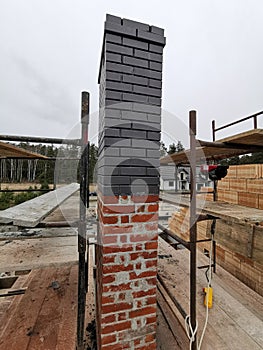 Installing house chimney blocks on the rooftop. Roofer decorate and protecting chimney bricklaing