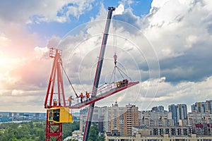 Installing the jib of a construction crane using another crane on the truck, the work of the builders of climbers at a height,