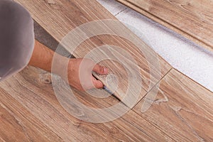 Installing laminate flooring. Carpenter lining parquet boards to