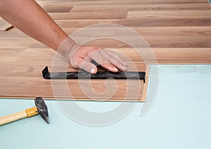 Installing laminate flooring. Man Installing New Laminate Wood Flooring. Worker Installing wooden laminate flooring with hammer.