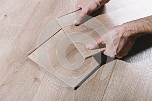 Installing laminate flooring in a room or office. Wooden parquet boards in the hands of a worker. Construction and