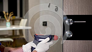 Installing a lock on the front door. A carpenter in a special uniform repairs the lock of the front door. Man with a screwdriver