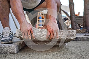 Installing new pavement or floor outside from large concrete tiles, closeup detail on male worker fitting stone block