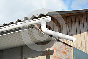 Installing plastic roof gutter with fascias board on old building.