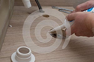 Installing the sink on a wooden countertop. The saw cut with acrylic sealant. Plumber work