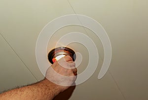 Installing a spot light, the hand inserts the lamp into the ceiling. Replacing a burned out incandescent bulb