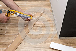 Installing white skirting board with caulking gun photo