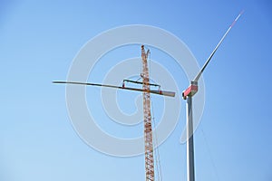 Installing a wind turbine, crane is lifting the second blade to install it to the rotor hub on the tower, heavy industry for
